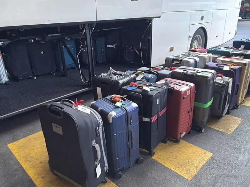Koffer aufgereiht vor dem offenen Gepäckraum eines Cars