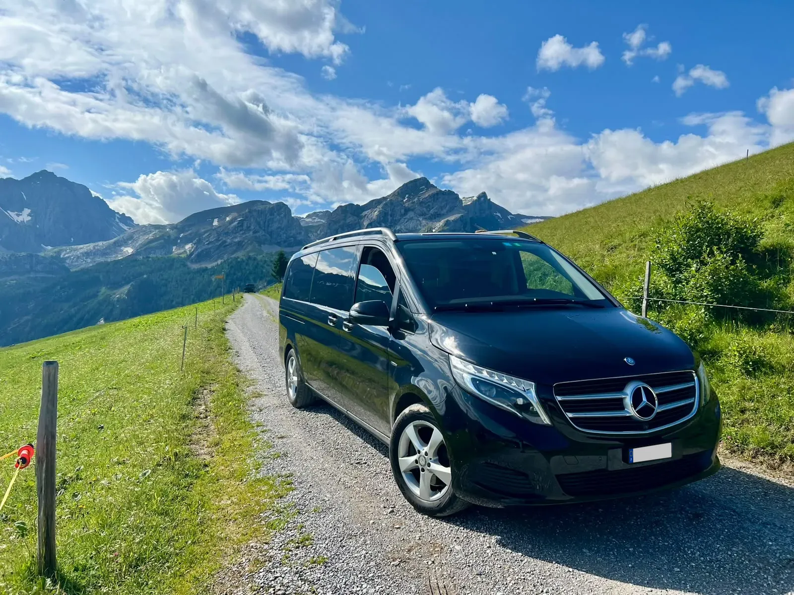Schwarzer Mercedes-V-Klasse-Van auf einer Bergstrasse in den Alpen