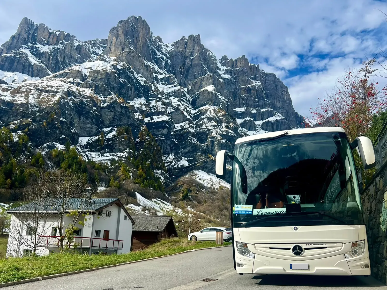 Car von Leonardo Travel in einem Dorf in den Schweizer Alpen, mit verschneiten Bergen im Hintergrund